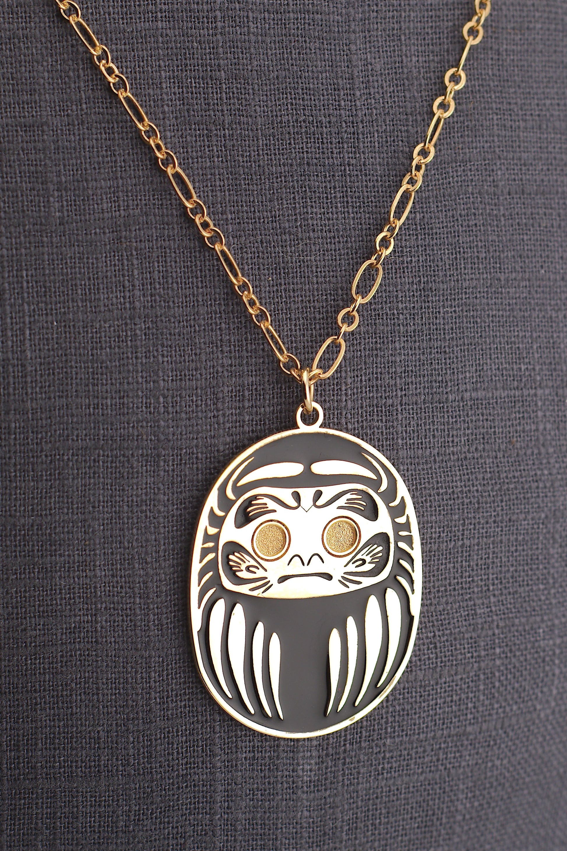 Collana Daruma Nera con ciondolo oro su sfondo grigio – simbolo successo e protezione contro le avversità Nuage d'Étoiles

